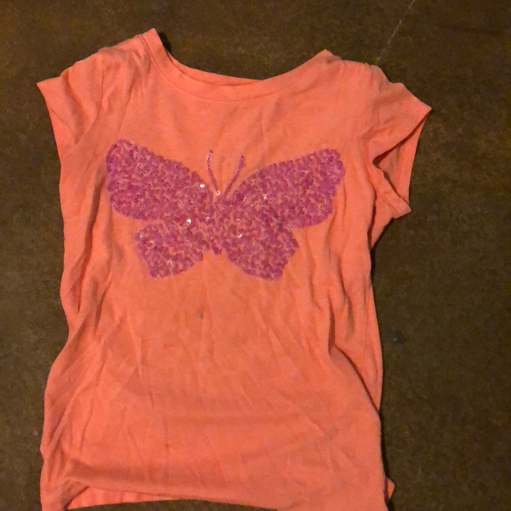 A coral shirt with a purple beaded butterfly
